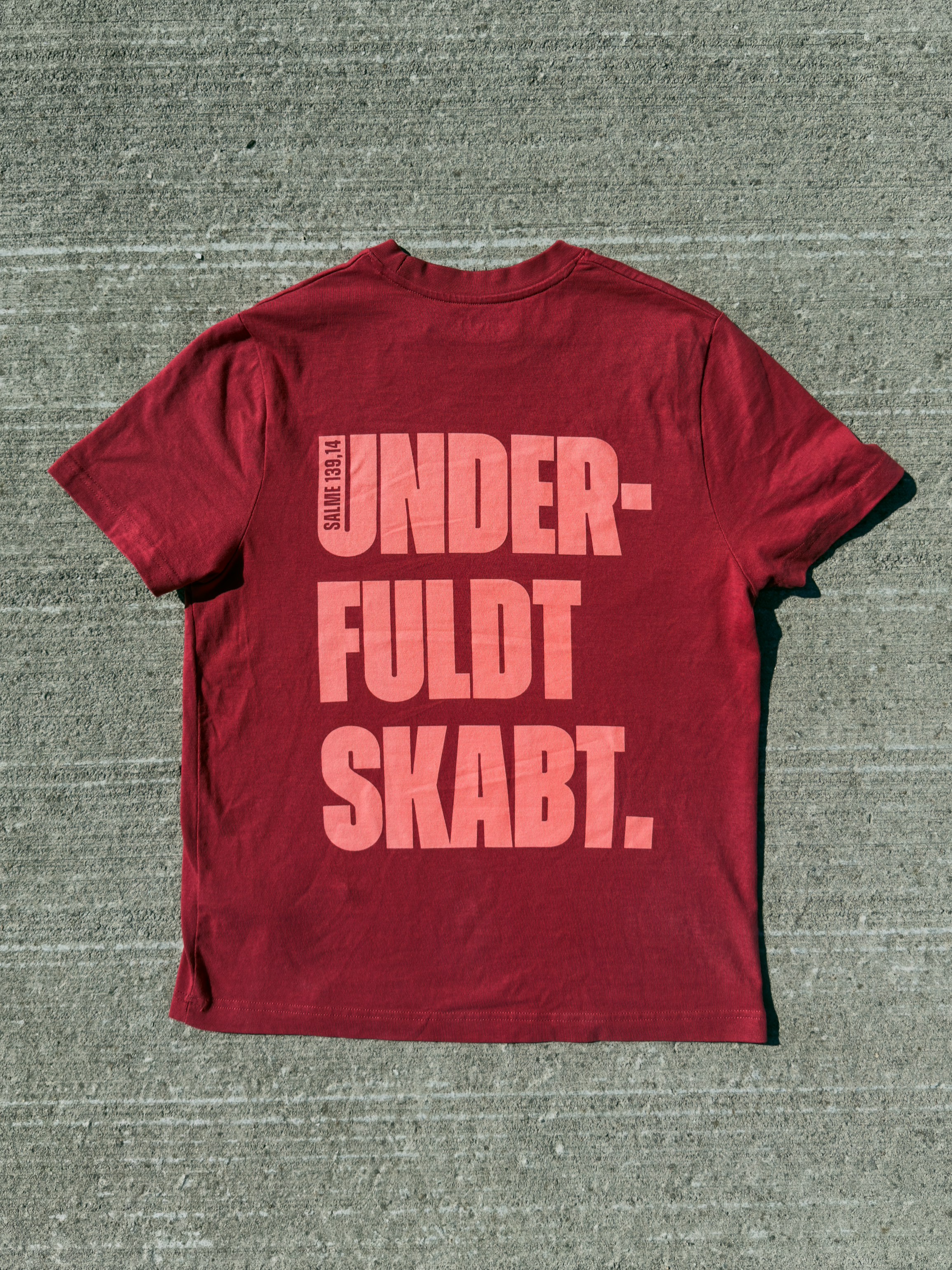 Underfuldt skabt – mørkerød kristen T-shirt liggende med UNDERFULDT SKABT-rygprint